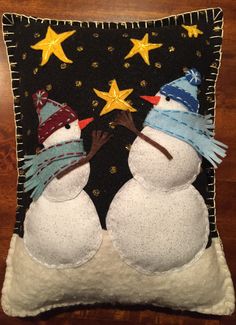 two snowmen wearing hats and scarfs on a pillow