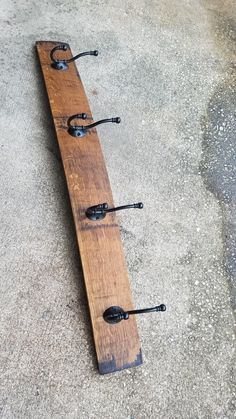 a long piece of wood with three hooks attached to it on concrete ground next to water