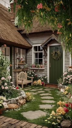 a garden with flowers and a bench in front of a small house that has a grass roof