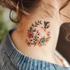 a woman's neck tattoo with colorful flowers and butterflies on the back of her neck