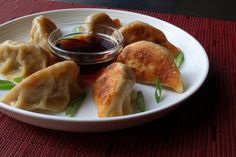 a white plate topped with dumplings and dipping sauce