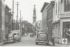 an old black and white photo of people walking down the street