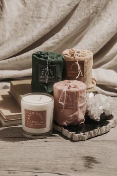 three candles sitting on top of a wooden table next to some books and soaps