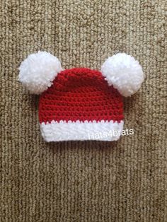 a red and white knitted hat with pom - poms