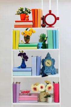 a white shelf filled with lots of books and vases on top of each other