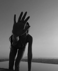 a woman reaching out her hand towards the water