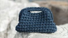 a crocheted blue purse sitting on top of a rock