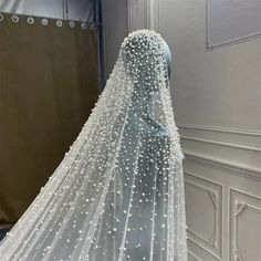 a white veil with pearls hanging from it's side in front of a mirror