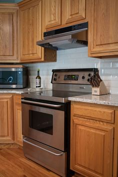 a stainless steel stove and oven in a kitchen with wooden cabinets, counter tops, and hardwood flooring