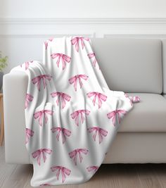 a white couch with pink bows on it and a blanket draped over the back of it