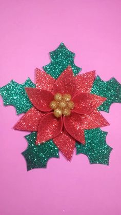 a red and green poinsettia with glitter on it's center, against a pink background