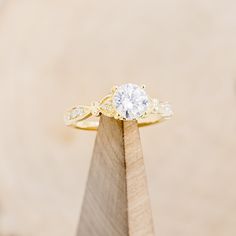 a close up of a ring on top of a piece of wood with a diamond in the middle