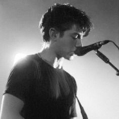 a young man is playing the guitar in front of a microphone while singing into a mic