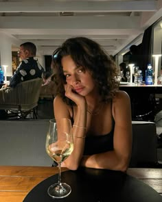 a woman sitting at a table with a glass of wine