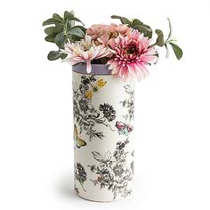 a white vase with pink flowers and green leaves on the inside is shown against a white background