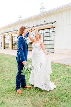 a bride and groom standing in front of a barn holding each other's hands