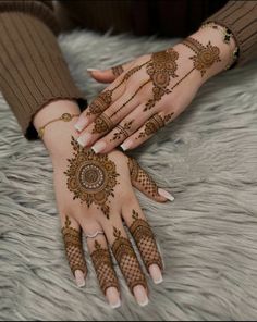 two hands with henna tattoos on them