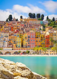 the colorful buildings are on top of the hill above the water