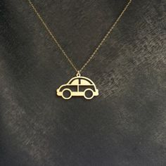 a gold necklace with a small car on it's front and back sides, hanging from a chain