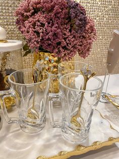 a table topped with glasses and a vase filled with purple flowers on top of it