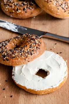 two bagels with white frosting and sprinkles next to a knife