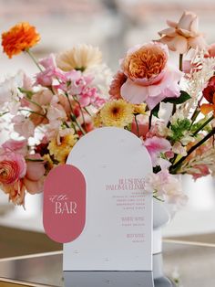 a vase filled with lots of flowers on top of a table next to a bar sign