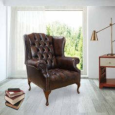 a brown leather chair sitting on top of a hard wood floor next to a window