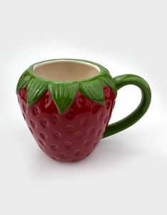 a ceramic strawberry mug with green leaves on it