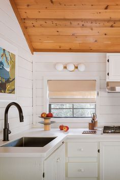 a kitchen with white cabinets and wood ceiling