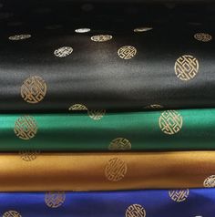 four different colored fabrics stacked on top of each other in various patterns and sizes, all with gold foiling