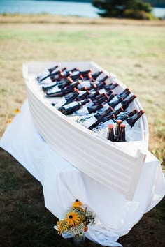 there is a boat with bottles on it and flowers in the grass next to it