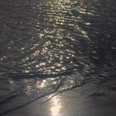 the sun shines brightly on the water at the beach shore line as it reflects off the wet sand