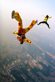 two people doing tricks in the air on parachutes