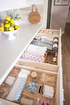 an open drawer in a kitchen with lemons on the counter and other items inside