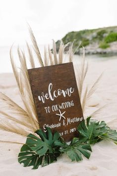 a welcome sign is placed on the sand with some plants in front of it that says welcome to our guests