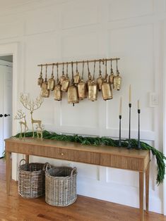 a wooden table topped with two baskets filled with christmas decorations and bells hanging from the wall