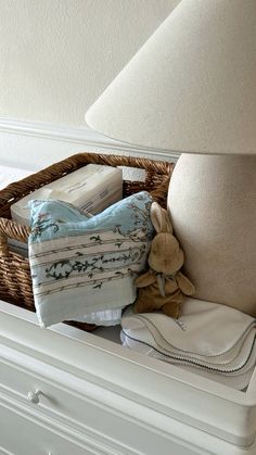 a basket filled with folded towels next to a lamp