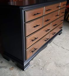 an old dresser is painted black and brown