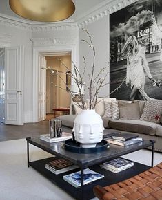 a living room filled with furniture and a large painting on the wall above it's coffee table