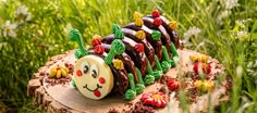 a cake shaped like a caterpillar on top of a tree stump in the grass