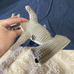 a hand holding a small stuffed animal in it's right hand on a blue background