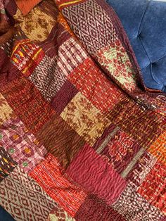 a blue couch with a patchwork blanket on it