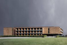 a large building sitting on top of a lush green field next to a tall grass covered hillside