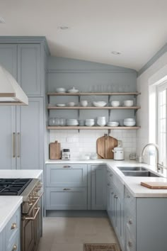 a kitchen with blue cabinets and white counter tops, along with open shelves on the wall