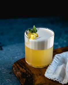 a small glass filled with lemonade on top of a wooden cutting board next to a napkin