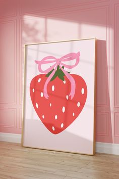 a strawberry with a pink bow on it is in front of a pink wall and wooden floor