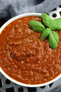 a white bowl filled with tomato sauce and basil