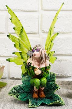 a fairy figurine sitting on top of a leaf