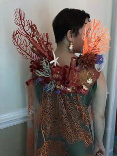 a woman is standing in front of a wall with red corals and starfish on it