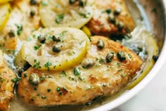 a pan filled with chicken, potatoes and lemons on top of a white table